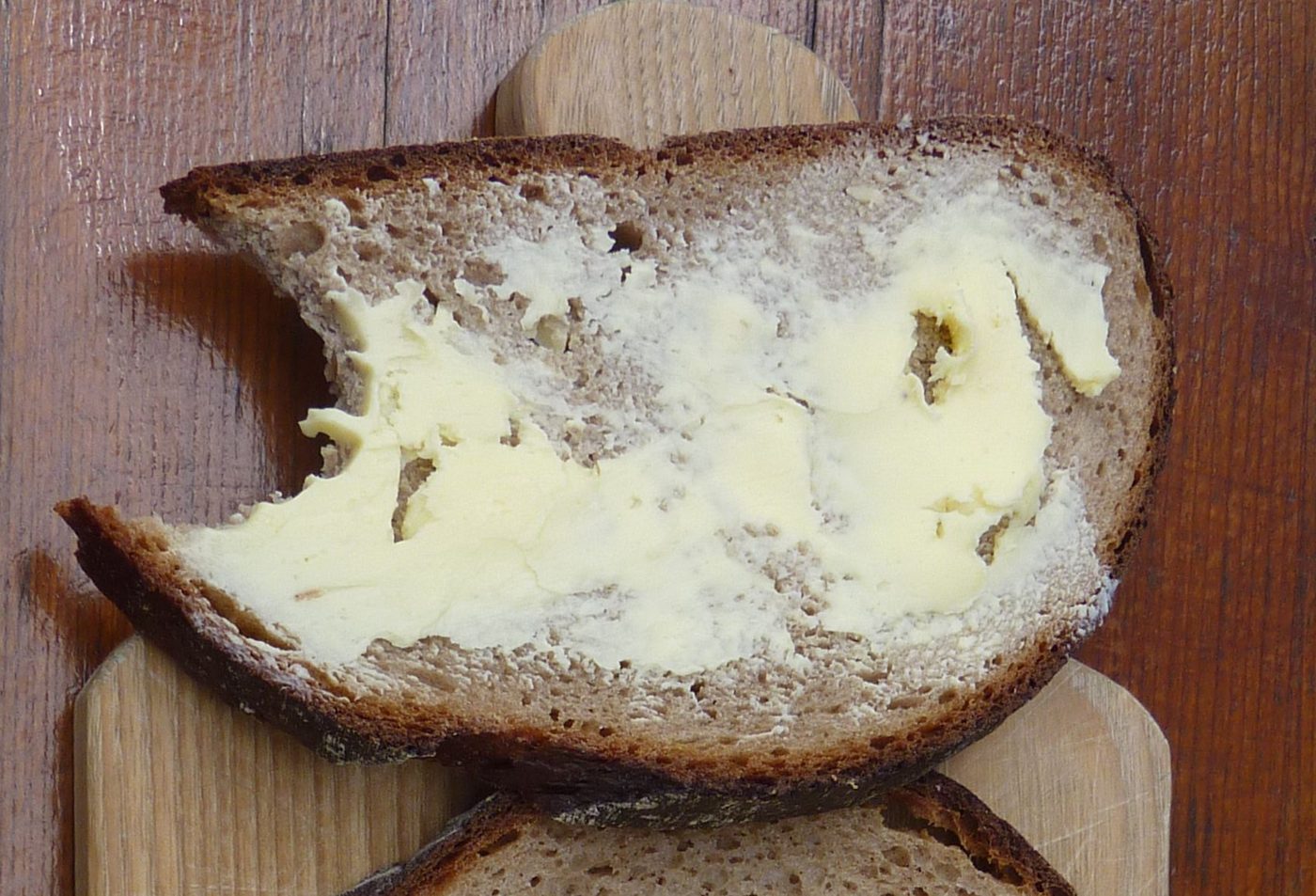 Rebanada de pan de centeno con mantequilla, con una mordida.