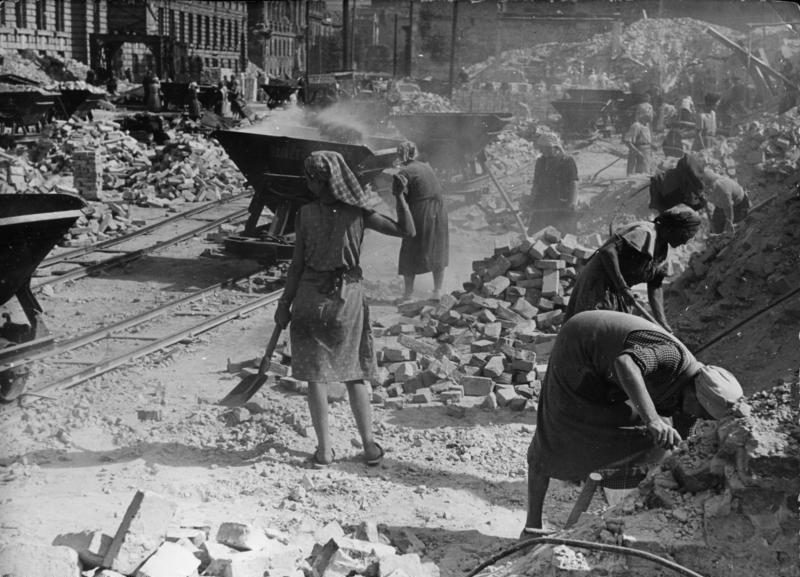 Mujeres limpiando escombros en una calle de Berlín en 1945, con vagonetas de ladrillo al fondo.